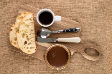 Cam kavanoza yayılmış lezzetli çikolata, jüt kumaşlı ekmek, yakın plan, üst manzara..