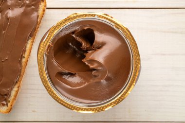 Cam bir kavanozda çikolata ezmesi, ahşap bir masa, üst manzara, makro.