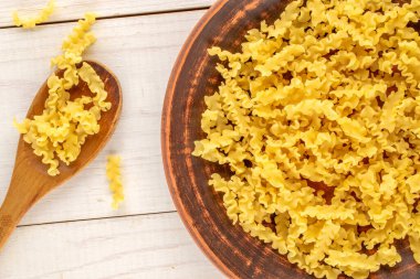 Ahşap bir masada, dalga şeklinde ham makarna, yakın plan. Üst görünüm.