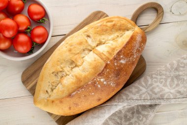 Bir somun beyaz buğday ekmeği ve domatesler ahşap bir masada, yakın plan, üst manzara.