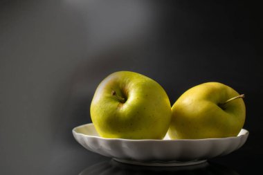 Arkaplanda seramik bir tabakta elmalar, yakın plan..