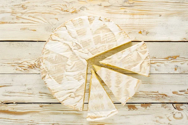 Ahşap bir masanın üzerinde mutfak aletleri olan peynirli peynir, yakın plan. Üst görünüm.