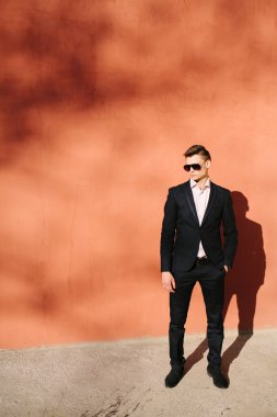 bir tuğla duvar bir arka plan üzerinde siyah elbiseli genç adam