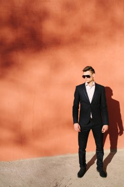 bir tuğla duvar bir arka plan üzerinde siyah elbiseli genç adam