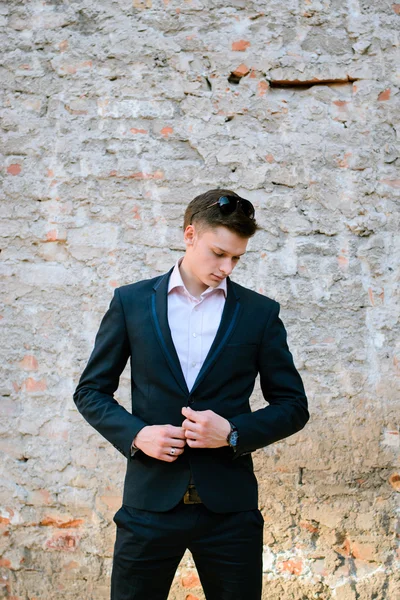 bir tuğla duvar bir arka plan üzerinde siyah elbiseli genç adam