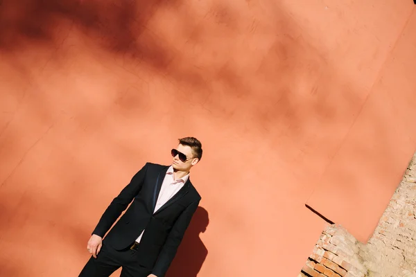 Bir tuğla duvar bir arka plan üzerinde siyah elbiseli genç adam — Stok fotoğraf