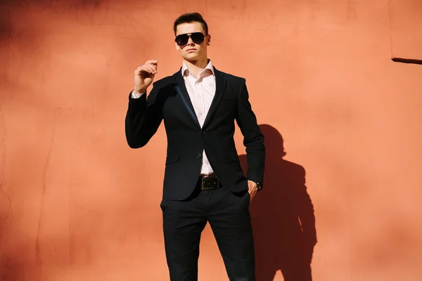 Young man in a black suit on a background of a brick wall — Stock Photo, Image