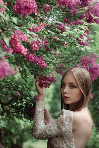 Beautiful young girl in a flowering lilac. Garden of lilac bloom