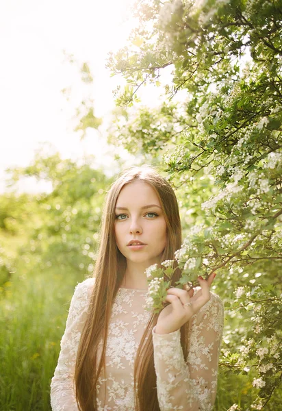 Beautiful young girl in a flowering lilac — Stock Photo, Image