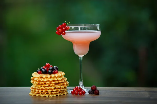 Glas met roze cocktail en wafels op groene achtergrond bokeh — Stockfoto