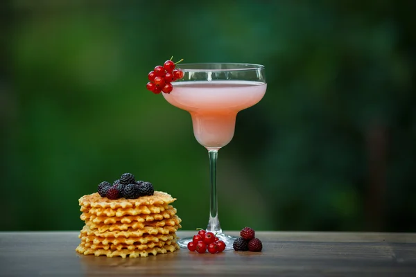 Glas met roze cocktail en wafels op groene achtergrond bokeh — Stockfoto