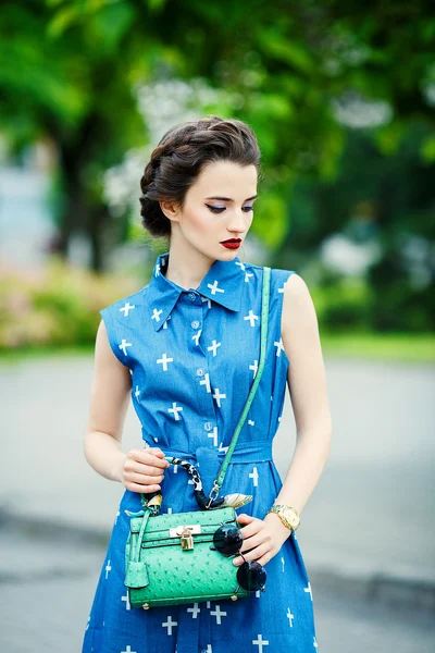 Menina bonita em um vestido azul na mira com pequena bolsa verde — Fotografia de Stock