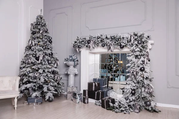 Hediyelerle süslenmiş Noel ağacı şöminenin içinde duruyor.