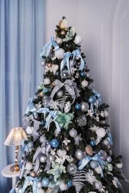 Üzerinde mavi, beyaz ve gümüş toplar olan Noel ağacı..