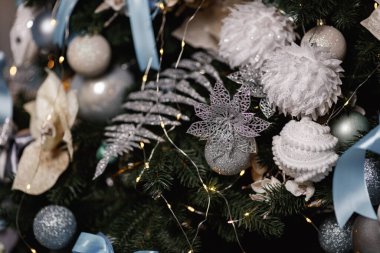 Noel ağacında asılı duran mavi, beyaz ve gümüş toplar ve oyuncaklar.