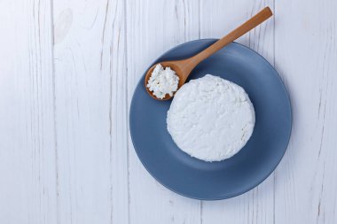 Tahta kaşıkla tabakta taze çiftlik yapımı süzme peynir..