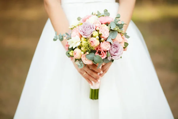 La mariée tient le bouquet de fleurs dans sa main, le bouquet floral de mariage — Photo