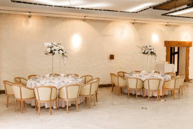 Düğün ziyafeti masalarında beyaz renkli çatal bıçaklı şenlikli çiçek dekoru. Farklı doğal renklerde güller, şakayıklar, anturyum. Lüks düğün, parti, doğum günü.