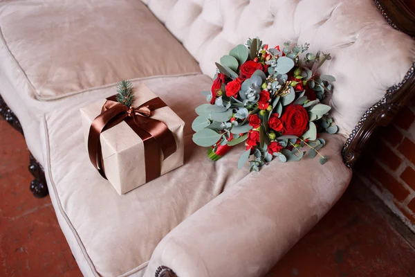 Bridal bouquet and a gift  on the couch — Stock Photo, Image