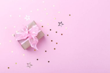 El işi kağıda sarılı bir hediye kutusu. İpek kurdele ve pembe arka planda yıldızlar.