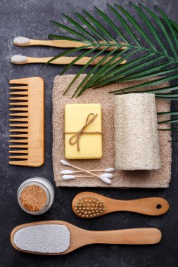 Doğal bambu diş fırçaları, siyah diş tozu, siyah arka planda saç tarağı, sabun ve sünger, sıfır atık ürünü, doğal ağız temizliği, kopyalama alanı