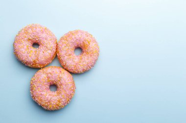 Mavi arkaplanda pembe çörekler ve şekerler, düzlüğü kopyala