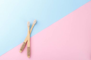Pembe mavi arka planda doğal bambu diş fırçaları, sıfır atık ürün, doğal ağız temizliği.
