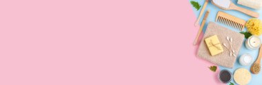 Sıfır atık tekrar kullanılabilir banyo öğeleri mavi pembe arka planda, ahşap tarak, diş fırçası, deniz süngeri, kulak çubuğu, katı sabun, shea veya hindistan cevizi yağı, düz konum afişi kopya alanı ile