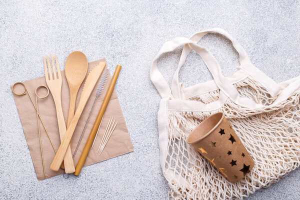 Zero waste bamboo tableware, eco friendly paper cup and napkin, straw, bag, wooden cutlery on natural stone background. Top view copy space