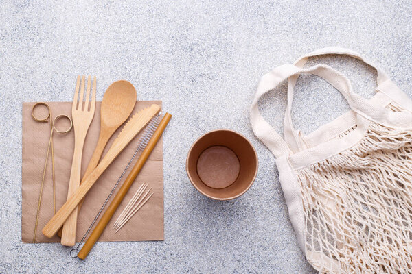 Zero waste bamboo tableware, eco friendly paper cup and napkin, straw, bag, wooden cutlery on natural stone background. Top view copy space