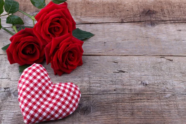 Corações e um buquê de rosas vermelhas em tábua de madeira — Fotografia de Stock