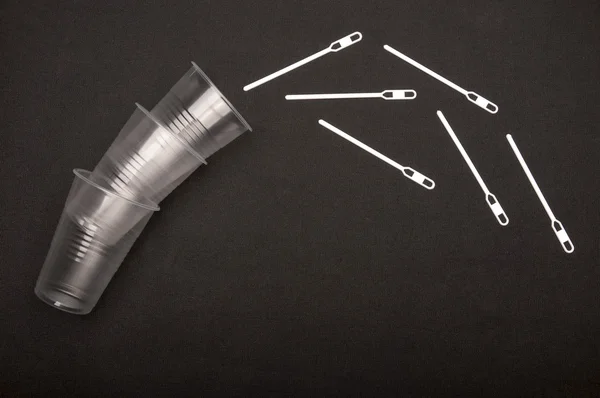 Beyaz siyah arka plan üzerine şeffaf plastik bardak yakınındaki sopa karıştırma.