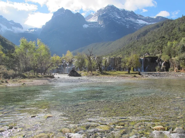 Beyaz su nehir şelale kayalıklarla ve brooks jade dragon snow mountain, lijiang, yunnan Çin'ın eteklerinde