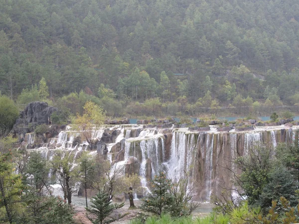 Beyaz su nehir şelale kayalıklarla ve brooks jade dragon snow mountain, lijiang, yunnan Çin'ın eteklerinde