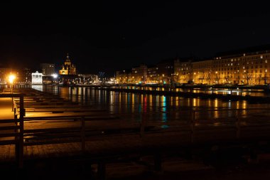   Helsinki 'nin gece manzarası, Katadanokka ve Krununhakka bölgelerinin ön planda olduğu Finlandiya Körfezi ve tekne rıhtımı manzarası