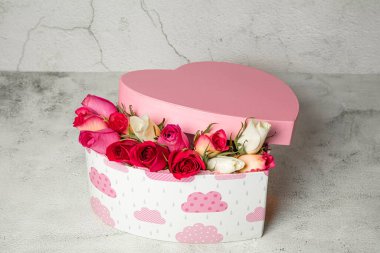 Hafif arka planda bir kutuda güller ve kalp kutusu dekoru. Tatil, yıldönümü, doğum günü acil servisi için tebrikler.