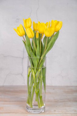 Sarı çiçekler, vazodaki laleler. Hafif bir arkaplanda. Paskalya için tebrikler. Acil
