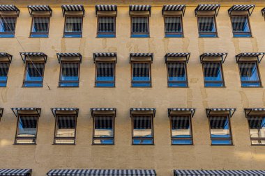 Oteldeki cam pencerenin üzerinde mavi ve beyaz tenteler, gölgeleme için konsept dekorasyon