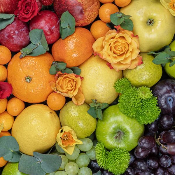 A large bouquet of fruits. Grapes, apples, oranges, kiwi, tangerines, pomegranates and flowers. View from above .