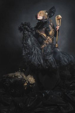 Amazon, kadın savaşçı, siyah takım elbiseli efsanevi yaratık, gözleri kapalı ve ejderha. Fotoğraf stüdyoda. Masal, efsane, tiyatro, sinema konsepti.