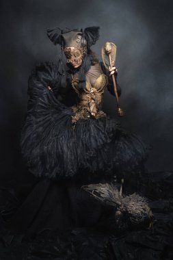 Amazon, kadın savaşçı, siyah takım elbiseli efsanevi yaratık, gözleri kapalı ve ejderha. Fotoğraf stüdyoda. Masal, efsane, tiyatro, sinema konsepti.