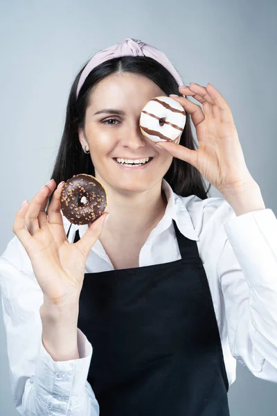 Woman pastry chef with donuts in her hands. Photo in the studio. Concept. Naturalness, Cooking. Tricks  confectioner's advice, trends. Business. Hobbies and activities,