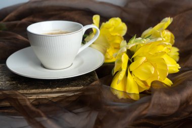 Durgun hayat. Sarı ve turuncu laleler, bir fincan kahve ve eski kitap. Tebrik kavramı