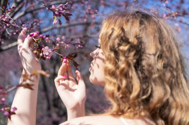 Genç bir kızın sırt portresi. Sakura tomurcuklarına bakıyor.