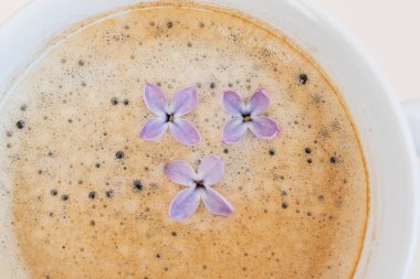 Kahveli fincanda leylak ve mor çiçekler. Yakın plan. Kavram, sıcaklık, susuzluğunuzu giderin, yaz tatili, yazlık bir yer var.