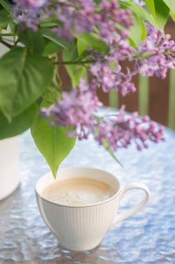 Masanın üzerinde bir buket leylak ve bir fincan kahve. Kavram, rahatlama.