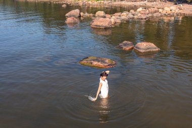 A young woman walks on the water. Lady bathes. Concept of summer vacation, skin and health care, relaxation.