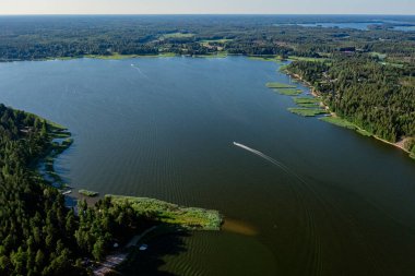 Gökyüzünden deniz manzarası ve yeşil sularda yüzen bir tekne. İskandinavya, Finlandiya. Bir insansız hava aracının fotoğrafı.
