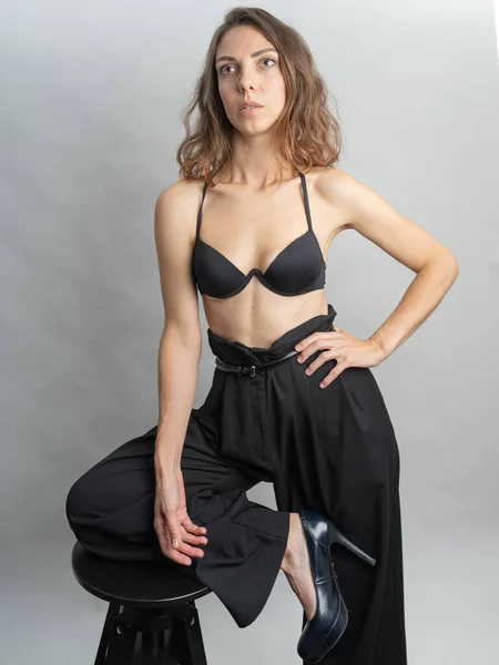 Model, esmer, stüdyoda beyaz arka planda poz veren. Beyaz bir gömlek giyiyor, siyah bir saç stili. Bele fotoğraf.