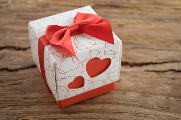 Κιβώτιο δώρων με δύο κόκκινες καρδιές στην πλευρά σε φόντο ξύλινη — Φωτογραφία Αρχείου